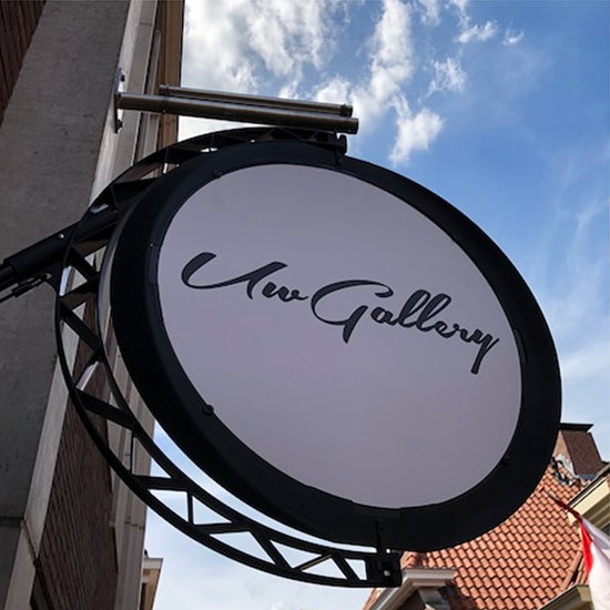 Rond uithangbord aan een gevel met de tekst 'Uw Gallery'