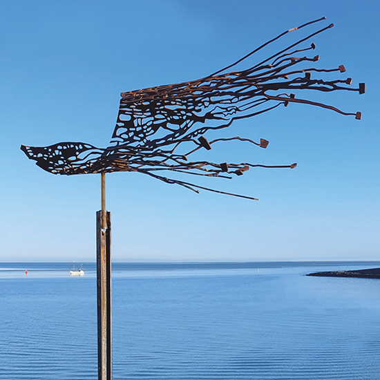 Cortenstalen beeld dat lijkt te wapperen in de wind, geplaatst op een sokkel in het water, met nautisch geïnspireerde uitsparingen.