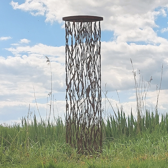 beeldentuin Fransje Versloot Lang gerekte cortenstalen beeld met organische uitsparingen die doen denken aan vormen uit de zee, buiten in het gras geplaatst.