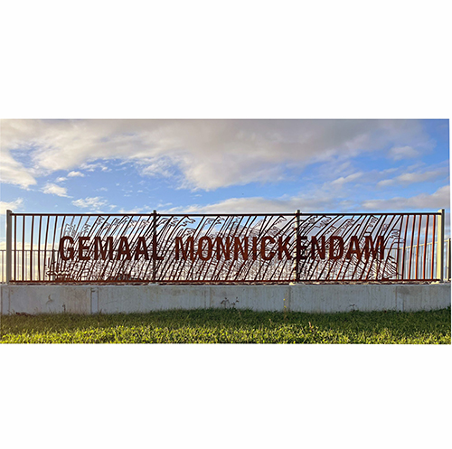 Cortenstalen hek met de tekst ‘gemaal monnickendam’, waarvan de spijlen zijn geïnspireerd op de vorm van riet.